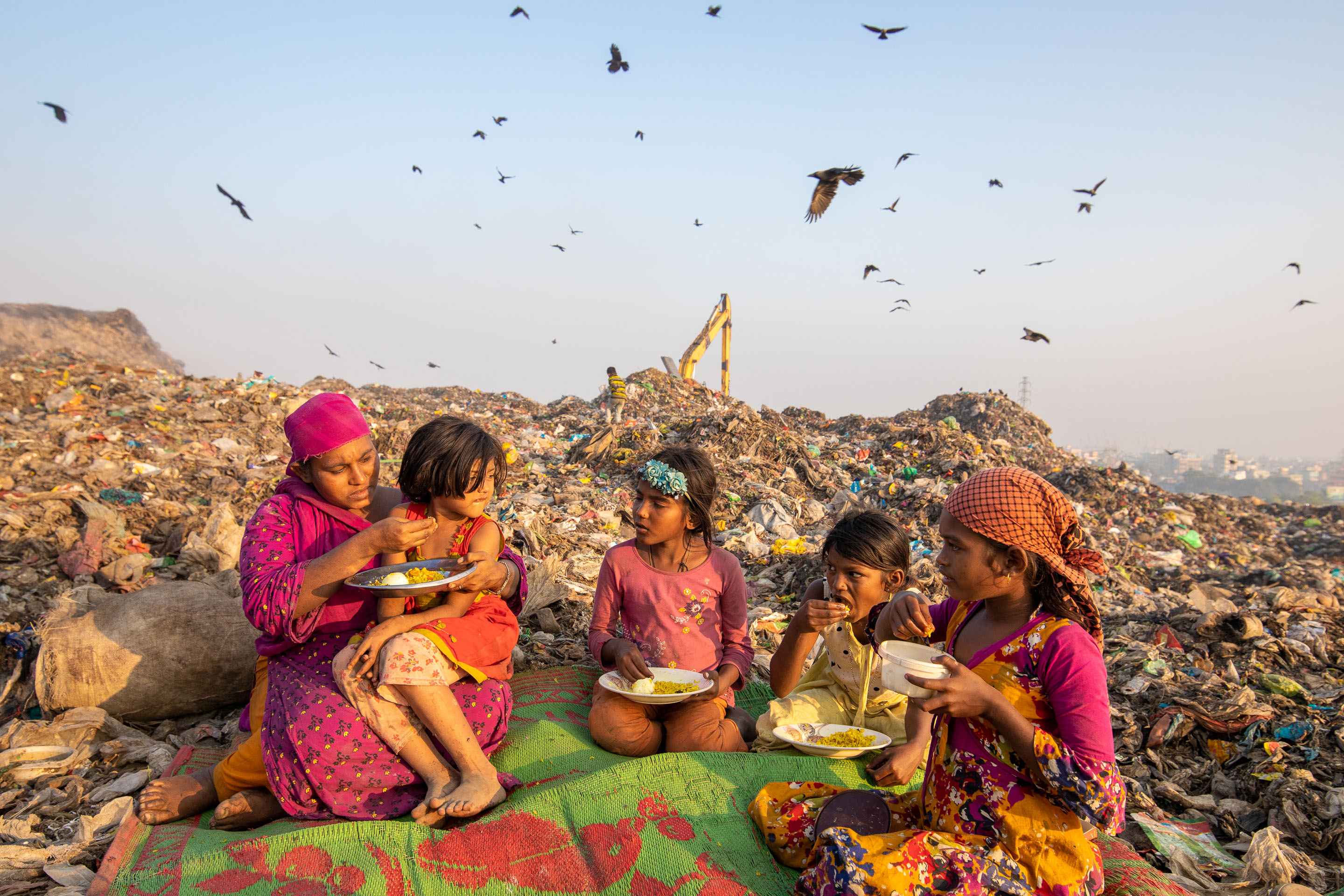 Childrens are eating lunch in a garbage field